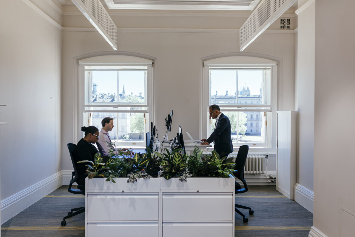 Office desk space in OAB - colleages working at desks, sitting and standing