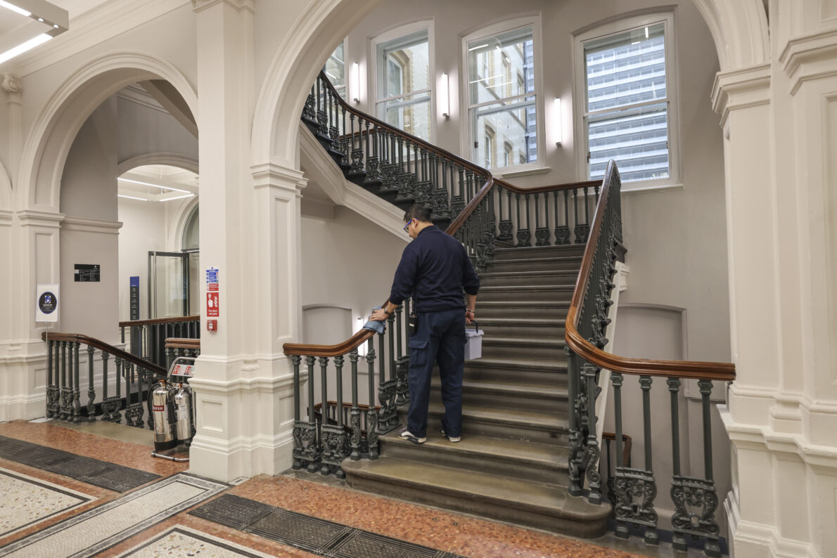 Cleaner wiping down OAB Staircase - large luxurious staircase
