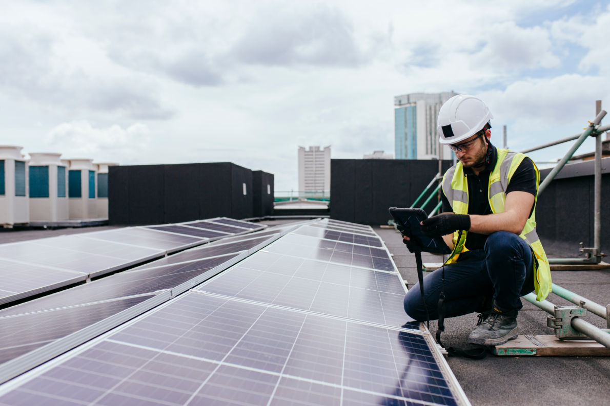 Builder on the roof surveying solar panels
