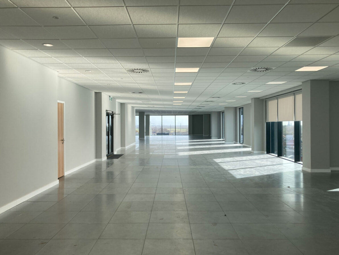 Unfurnished, open-plan office floor in Quay House before the interior fit-out, showing the wide, empty space and large windows.