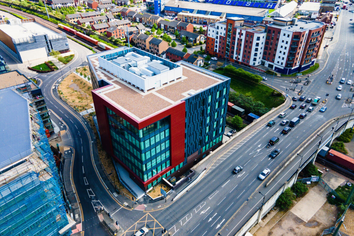 Aerial view of the modern, multi-story Government Hub (Quay House) building at Fletton Quays, Peterborough, surrounded by roads and adjacent regeneration developments.