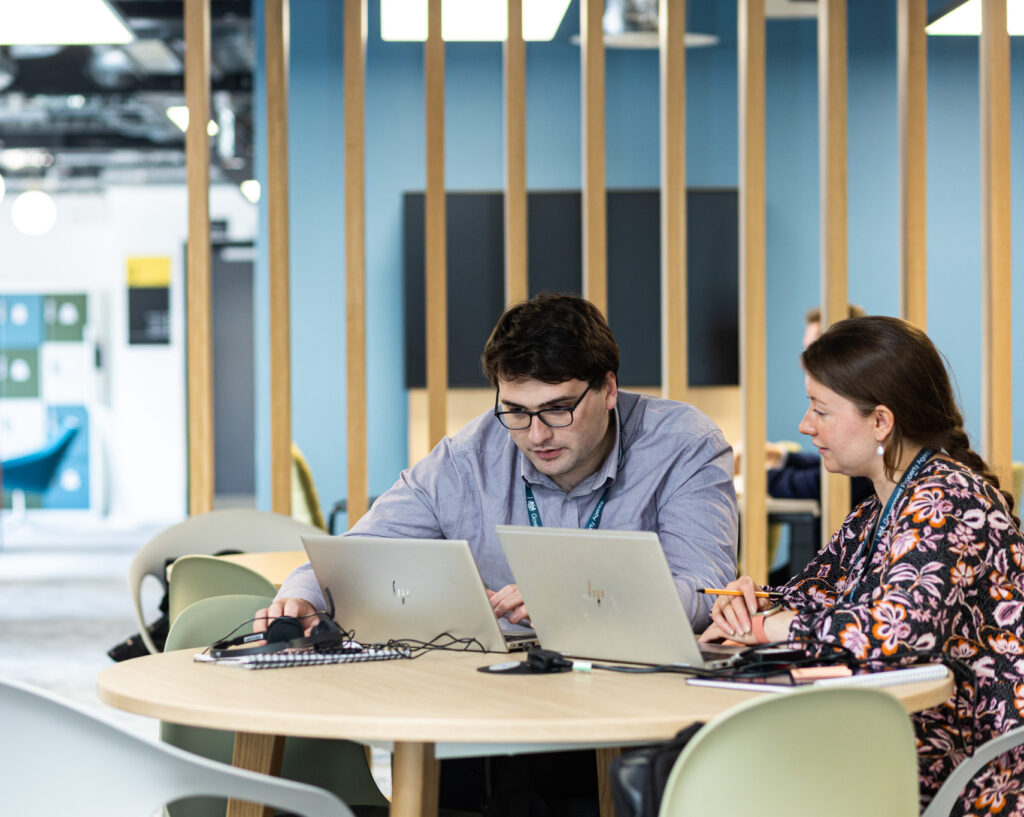 two people talking and viewing information on a laptop