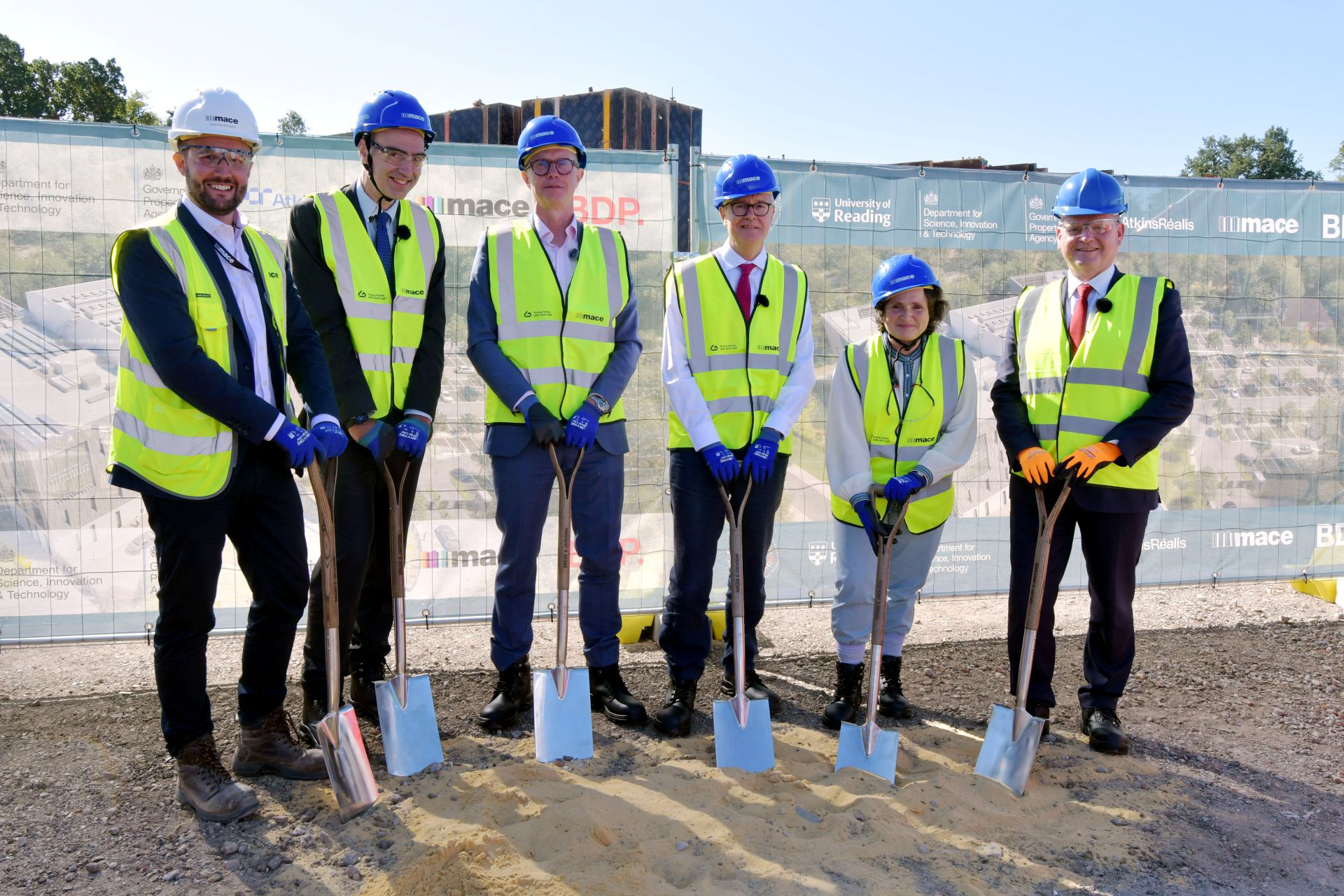 6 leaders stand at the site holding spades to initiate the ground breaking ceremony